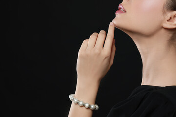 Poster - Young woman wearing elegant pearl bracelet on black background, closeup. Space for text