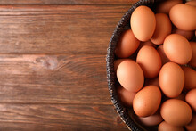Raw Chicken Eggs In Wicker Basket On Wooden Table, Top View. Space For Text