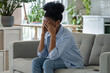 © DimaBerlin - Hopeless African American female suffering from of wrong decision crying sitting on sofa alone at home. Lonely black woman holding head in hand feeling desperate abused. Girl frustrated about problem.