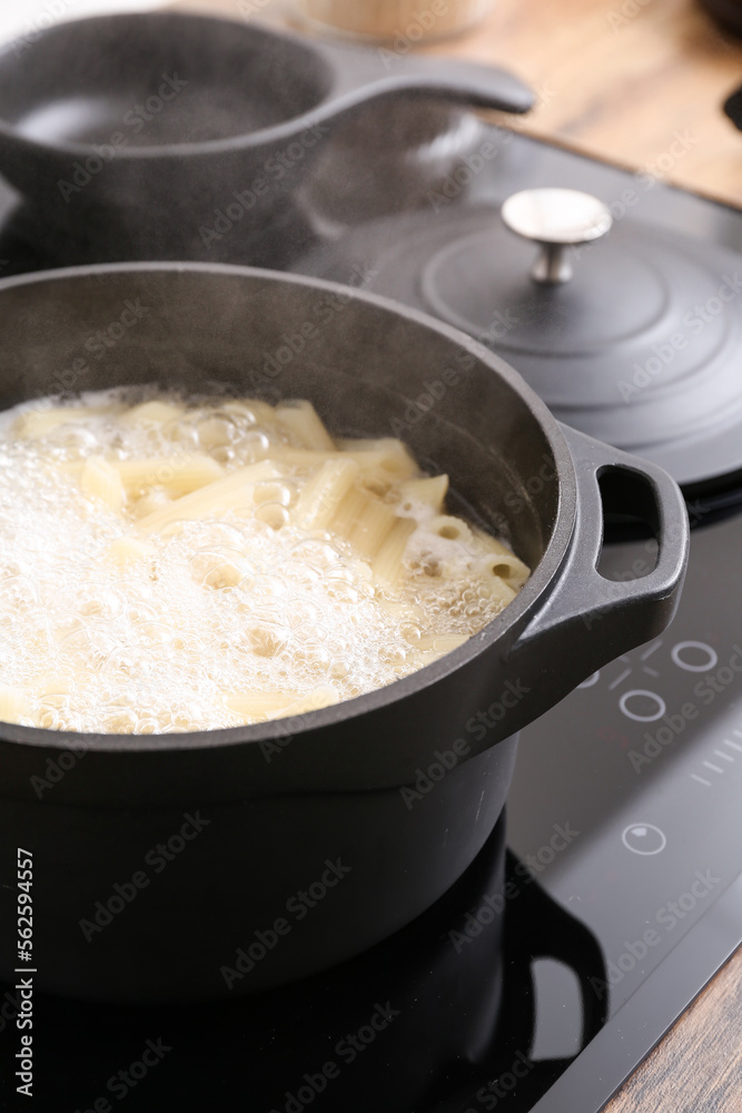 Cooking pot with boiling pasta on electric stove, closeup
