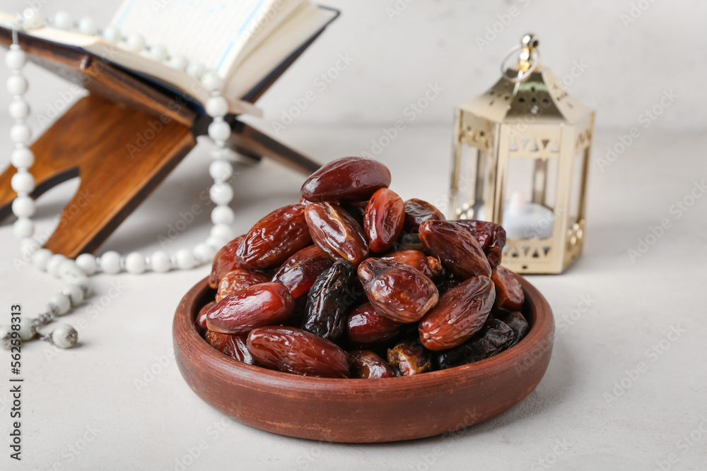 Bowl with dried dates for Ramadan on light table, closeup