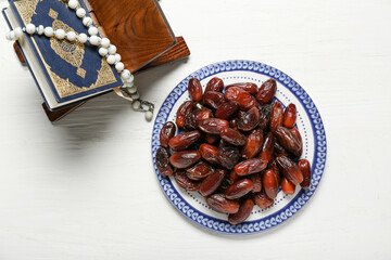 Wall Mural - Plate with dates, Koran and prayer beads for Ramadan on white wooden background