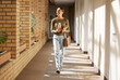 © K. A./peopleimages.com - Woman, student and university hallway with a person walking ready for learning and study. Smile, college and back to school happiness of a female tutor on campus going to class happy and alone