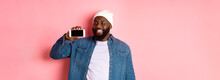 Online Shopping And Technology Concept. Happy Young African-american Man Smiling, Showing Smartphone Screen Horizontally With Satisfied Face Expression, Pink Background