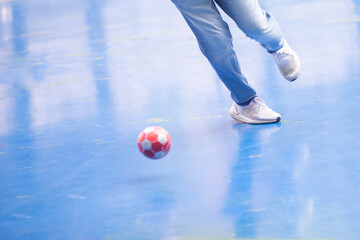 Sticker - Selective focus to foot of futsal player with blurry red ball.