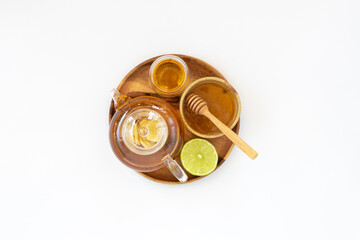 Wall Mural - Top view of a cup of tea with ginger root, lime, cinnamon and teapot on white background. Health drink concept.