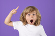 Surprised kid boy pointing up finger on blue background. Shocked kid pointing to copyspace, showing promo offers, points away. Excited emotions, shock, omg and wow expression.