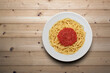 canvas print picture - plate of spaghetti with tomato sauce, viewed from above on a wooden surface
