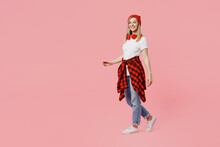 Full Body Smiling Cheerful Fun Happy Cool Young Woman Wear White T-shirt Red Hat Walking Going Looking Camera Isolated On Plain Pastel Light Pink Background Studio Portrait. People Lifestyle Concept.