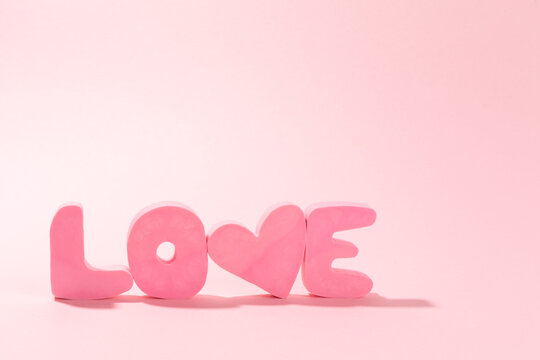 Word LOVE made of pink bubble letters and a heart on a pink background