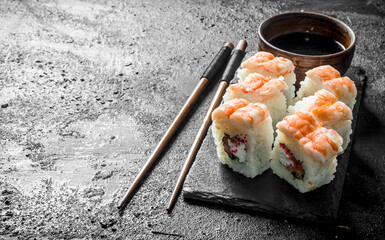 Sticker - Fresh sushi rolls with shrimp on a stand with soy sauce and chopsticks.