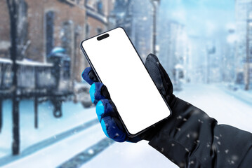 Fototapete - Using a mobile phone on the street while it is snowing. Isolated display for app promotion. Man's hand holding a phone with a winter glove