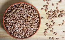 Dry Pinto Beans In Clay Bowl With Wooden Spoon In Rustic Kitchen