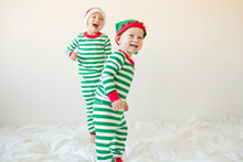Happy Baby Boys Standing On Bed Against White Background