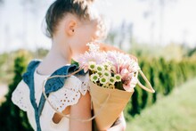 Young Girl In A Pretty Dress Holding A Bunch Of Beautiful Flowers