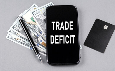 Poster - Credit card and text TRADE DEFICIT on smartphone with dollars and pen. Business concept