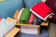 Woman holding clothes with Donate Box In her room. Gathering items to be donated to charity