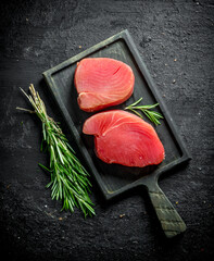 Poster - Pieces of raw tuna on a cutting Board with a bunch of rosemary.