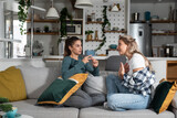 Fototapeta Młodzieżowe - Two young women friends, roommates, business partners and owners of a small business are arguing at home due to the inappropriate spending of money and increased expenses on household bills.