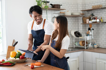 Wall Mural - Couple cooking together. Happy young couple cooking together in the kitchen. valentine day concept.