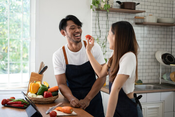 Wall Mural - Couple cooking together. Happy young couple cooking together in the kitchen. valentine day concept.