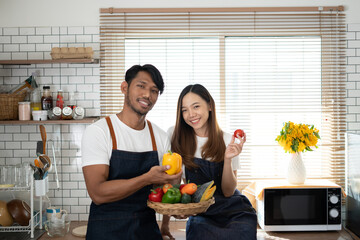 Wall Mural - Couple cooking together. Happy young couple cooking together in the kitchen. valentine day concept.