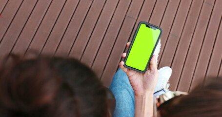 Friends holding cellphone looking at content. Mobile smartphone with green screen