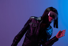 Confused Adorable Brunet Woman In Leather Jacket Specular Sunglasses Open Mouth Look Aside Posing Isolated In Blue Violet Color Light Background. Neon Party Cyberpunk Concept. Copy Space. Good Offer