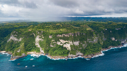 Wall Mural - Beautiful coastline aerial view from Saren Cliff Point. Clear water and rocks with cloudy sky. Nusa Penida, Indonesia.