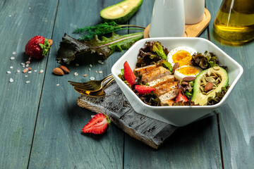 Wall Mural - Ketogenic low carbs diet, Plate with keto foods: two eggs, avocado, grilled chicken fillet, nuts, strawberries and fresh salad. Healthy fats, clean eating for weight loss. top view