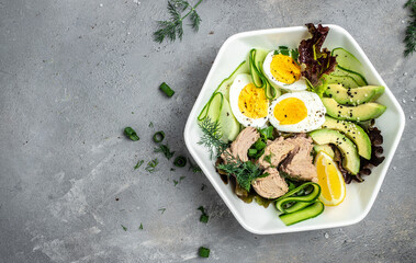 Wall Mural - Ketogenic low carbs diet, Plate with keto foods: two eggs, avocado, tuna, cucumber and fresh salad. Healthy fats, clean eating for weight loss. top view