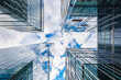 Look up to high skyscrapers corporate buildings with glass walls and reflecting beautiful cloudy sunny sky