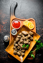 Sticker - Pieces of cooked liver on a cutting Board with lemon, herbs and tomato sauce.