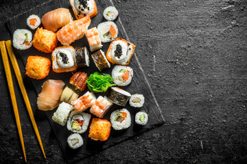 Sticker - Delicious rolls, sushi and maki on a stone Board with chopsticks.