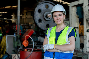 Wall Mural - Portrait of woman engineer wear white helmet arms crossed in uniform standing at industrial workshop. Copy space.