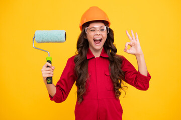 Sticker - Excited teenager girl. Painter in workshop. Renovation and repair. Teen girl in helmet with painting brush. Child in hard hat. Kid builder painter on construction site.