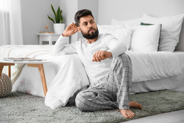 Wall Mural - Thoughtful young bearded man sitting on carpet at home