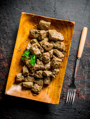 Canvas Print - Fried liver on a wooden plate with a fork.