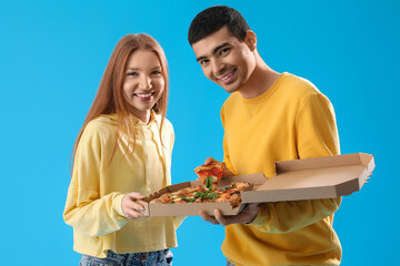 Wall Mural - Young couple with box of tasty pizza on blue background