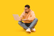 © Pixel-Shot - Handsome man with laptop biting nails on yellow background