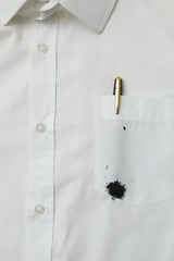 White shirt with stain of black ink and pen in pocket, top view