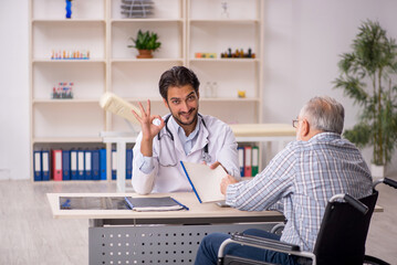 Old man in wheelchair visiting young male doctor