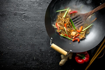 Sticker - Hot wok Chinese cellophane noodles in a pan with a spatula.