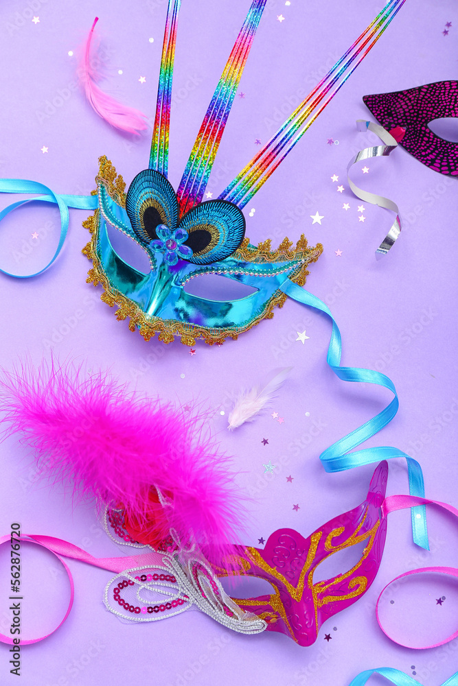 Carnival masks with confetti and serpentine on lilac background