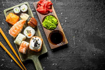 Canvas Print - Sushi, rolls and maki on the cutting Board with chopsticks and sauces.