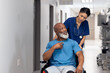 © WavebreakMediaMicro - Diverse female doctor pushing senior male patient in wheelchair in corridor, copy space