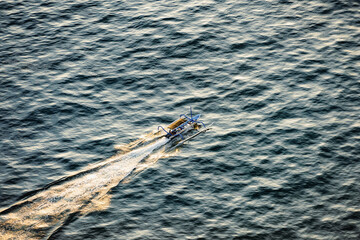 Wall Mural - View from above, stunning aerial view of a Jukung canoe sailing at sunset. Nusa Penida, Indonesia. A Jukung is a small wooden Indonesian outrigger canoe.
