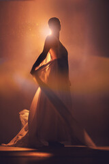 Orange lighting, fantasy and silhouette of woman with stylish dress for creative fashion, art deco and beauty. Dance, aesthetic and shadow of girl pose for dream, magic and freedom in glowing studio