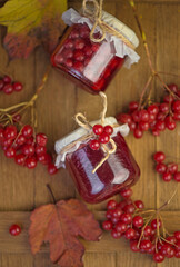 Sticker - Viburnum fruit jam in a glass jar on a wooden table near the ripe red viburnum berries. Source of natural vitamins. Used in folk medicine. Autumn harvest.