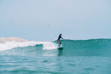 Pulled Back View Of A Female Surfer On A Wave